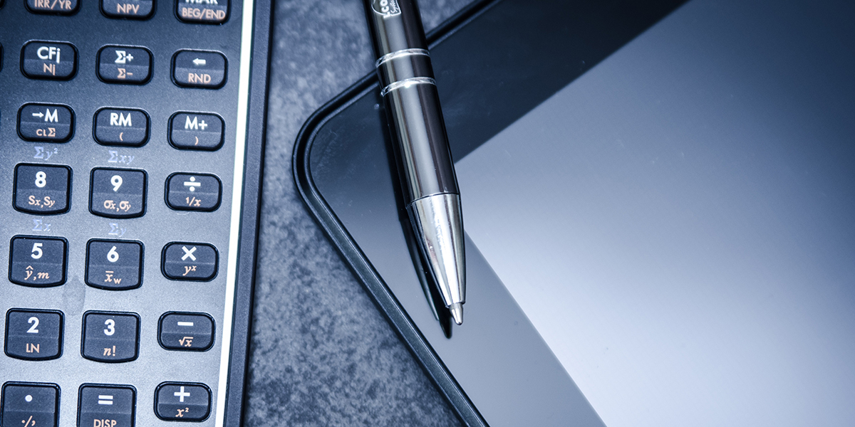 Calculator, tablet, and pen representing comprehensive financial planning
